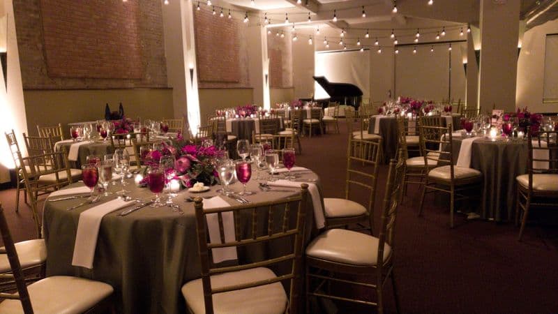 Formal dinner with gold chiavari chairs and floral centerpieces beside the grand piano