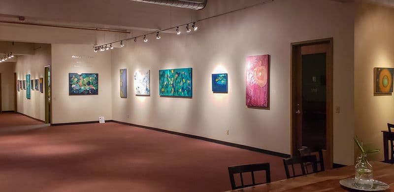 Gallery hallway hung with paintings under track lighting